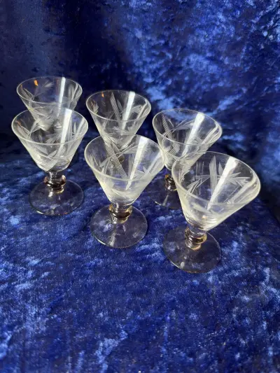 Sæt af seks ældre koniske cocktail- eller hedvinsglas med slebet blomster- og bladdekoration samt svagt rosa/røgfarvede fødder og knapper. Glas med denne type slibning og farvede detaljer minder stilm